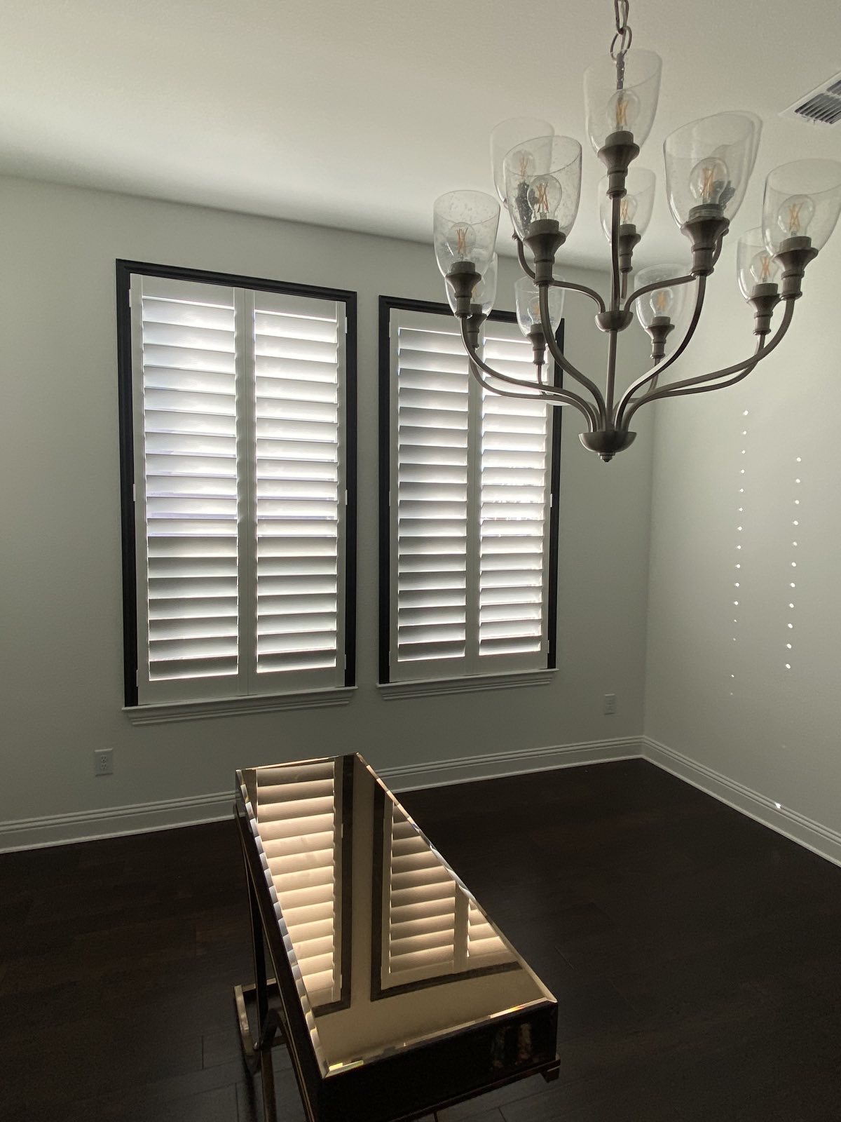 Contemporary black-frame plantation shutters with chandelier